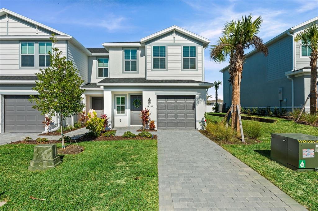 A two-story townhouse with light siding, a gray garage door, and a paved driveway — 14333 LILAC SKY TERRACE, BRADENTON, FL