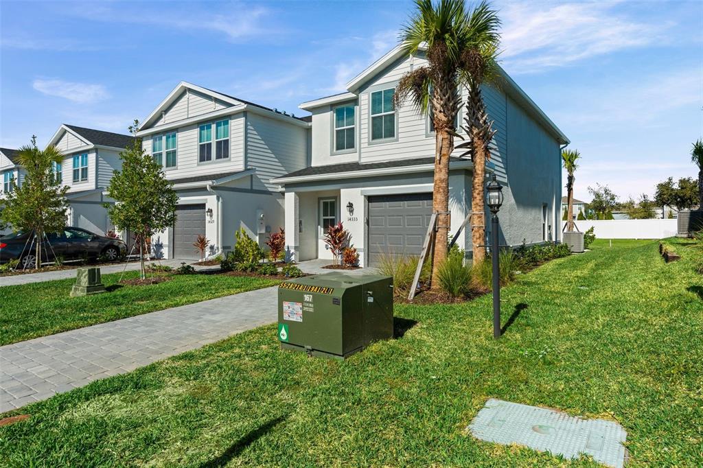 A two-story suburban house features a gray garage, a paved driveway, and a green transformer box — 14333 LILAC SKY TERRACE, BRADENTON, FL