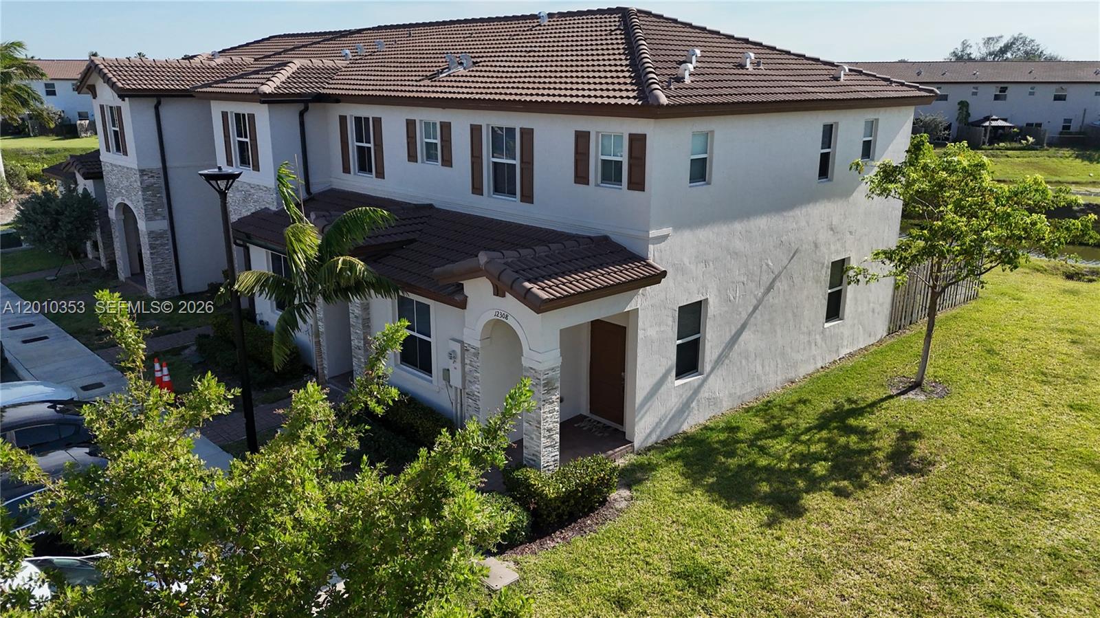 An aerial view of a two-story stucco townhouse with a brown tile roof — 12308 NW 23rd Ct # 12308, Miami FL 33167, MIAMI, FL