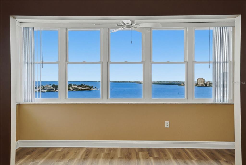 A room with light brown walls, wood-look flooring, and large windows overlooking a bay — 5108 BRITTANY DRIVE S UNIT 1006, ST PETERSBURG, FL
