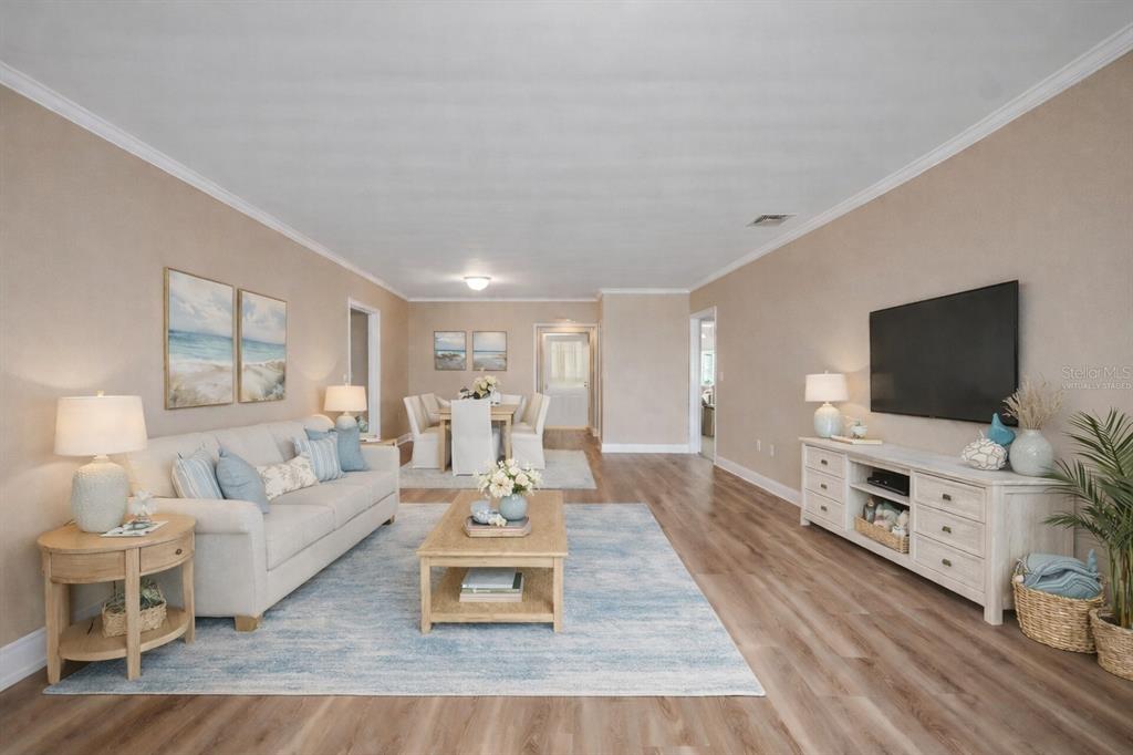A living and dining room with light wood flooring, neutral walls, and coastal-style furniture — 5108 BRITTANY DRIVE S UNIT 1006, ST PETERSBURG, FL