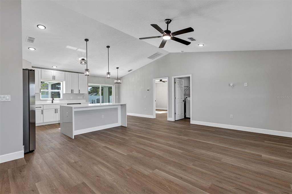 A bright, open-concept kitchen and living area with white cabinetry, a kitchen island, and flooring — 10449 SW 140TH AVENUE, DUNNELLON, FL