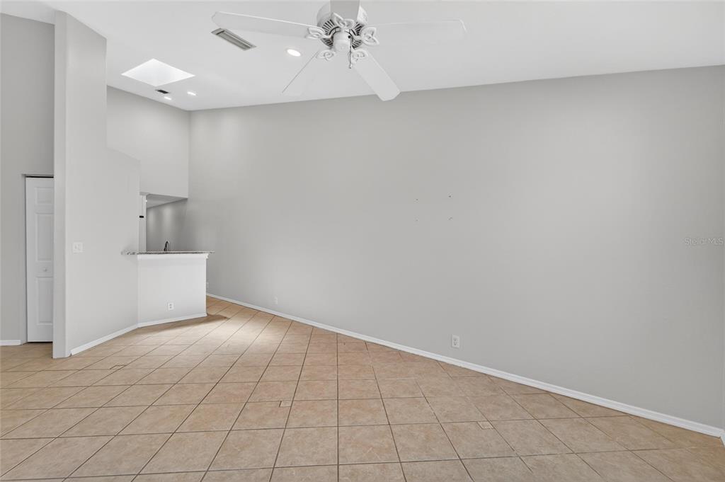 A spacious room with light gray walls, tile flooring, a ceiling fan, and a wet bar — 658 GREEN VALLEY ROAD UNIT B3, PALM HARBOR, FL