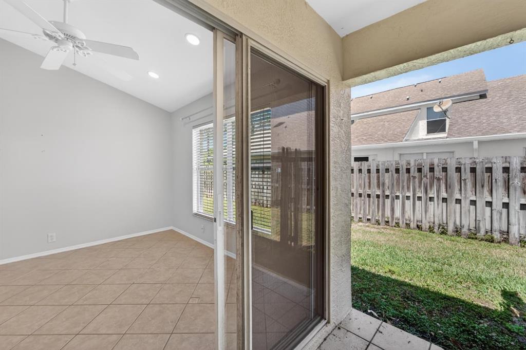 A tiled sunroom with a ceiling fan connects to a backyard through a sliding glass door — 658 GREEN VALLEY ROAD UNIT B3, PALM HARBOR, FL