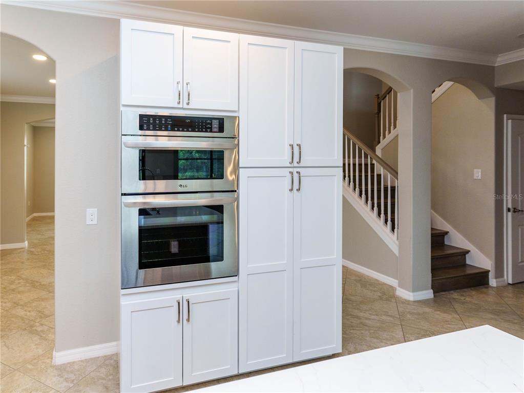 A kitchen features a dark wood island with a white countertop and white cabinetry — 1588 VIZCAYA LANE, NAPLES, FL