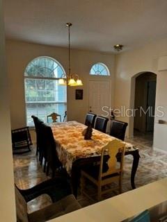 A dining room features a long table with chairs, a chandelier, and arched windows — 8806 CYPRESS HAMMOCK DRIVE, TAMPA, FL