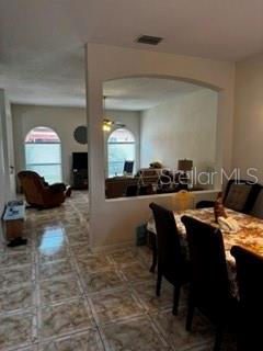 A dining area with a tiled floor opens into a living room through an arched wall — 8806 CYPRESS HAMMOCK DRIVE, TAMPA, FL