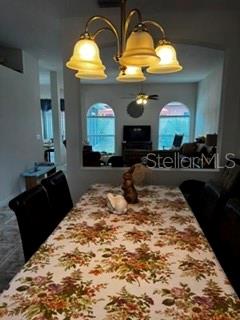A dining room features a floral tablecloth, a four-light chandelier, and a view into the living room — 8806 CYPRESS HAMMOCK DRIVE, TAMPA, FL