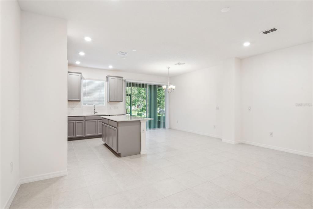 A kitchen with gray cabinets and a center island opens into a spacious dining area — 5756 SPOTTED HARRIER WAY, LITHIA, FL