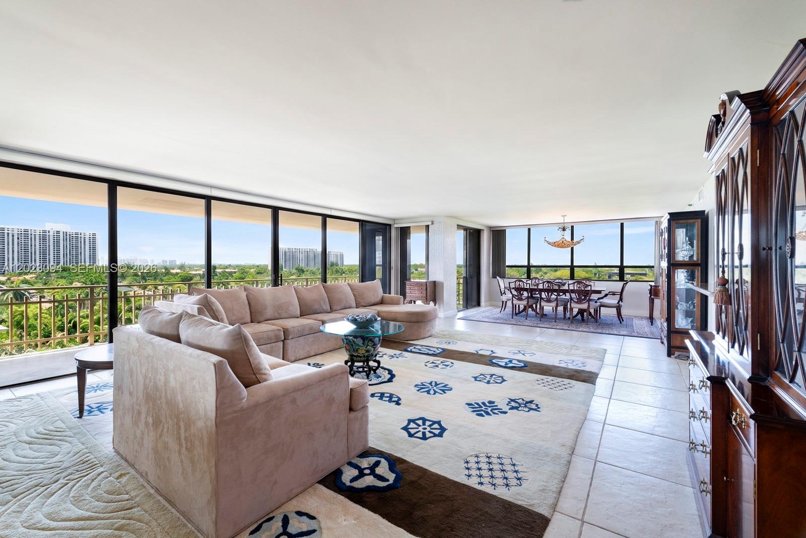 A spacious living and dining area features floor-to-ceiling windows, tile flooring, and a large sectional — 11113 Biscayne Blvd # 751, Miami FL 33181, MIAMI, FL