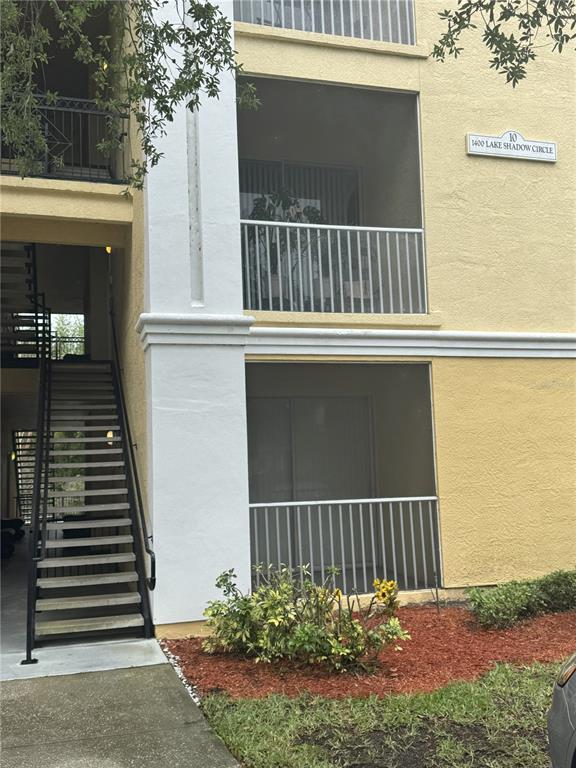 Exterior view of a two-story apartment building with screened balconies and an outdoor staircase — 1400 LAKE SHADOW CIRCLE UNIT 10103, MAITLAND, FL