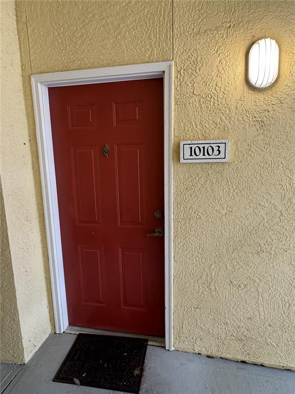 A red front door with a door knocker sits beside a wall-mounted light and unit number — 1400 LAKE SHADOW CIRCLE UNIT 10103, MAITLAND, FL