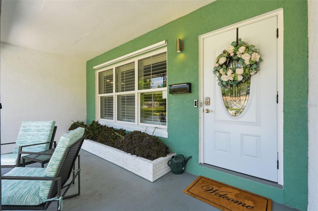 A green exterior wall features a white front door, a large window, and a planter box — 2900 PARK STREET N, ST PETERSBURG, FL