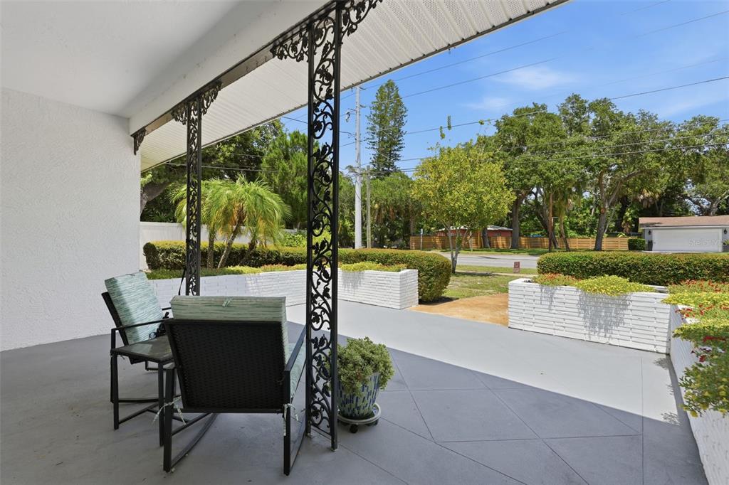 A covered patio features decorative iron columns, gray concrete flooring, and white brick planters — 2900 PARK STREET N, ST PETERSBURG, FL