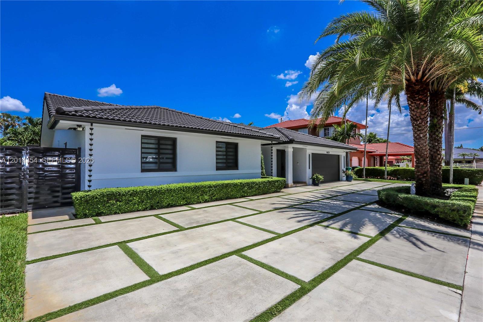 A white single-story house features a dark tiled roof, a garage, and a paved driveway — 14211 SW 31st St, Miami FL 33175, MIAMI, FL