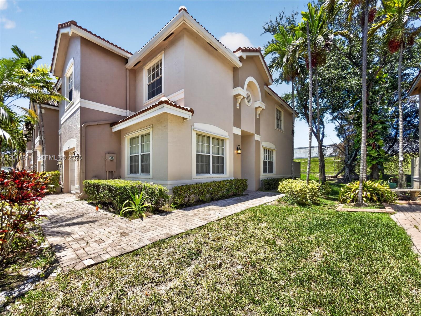 A two-story beige house with a tiled roof features a brick walkway and landscaping — 12415 SW 42nd St, Miramar FL 33027, MIRAMAR, FL