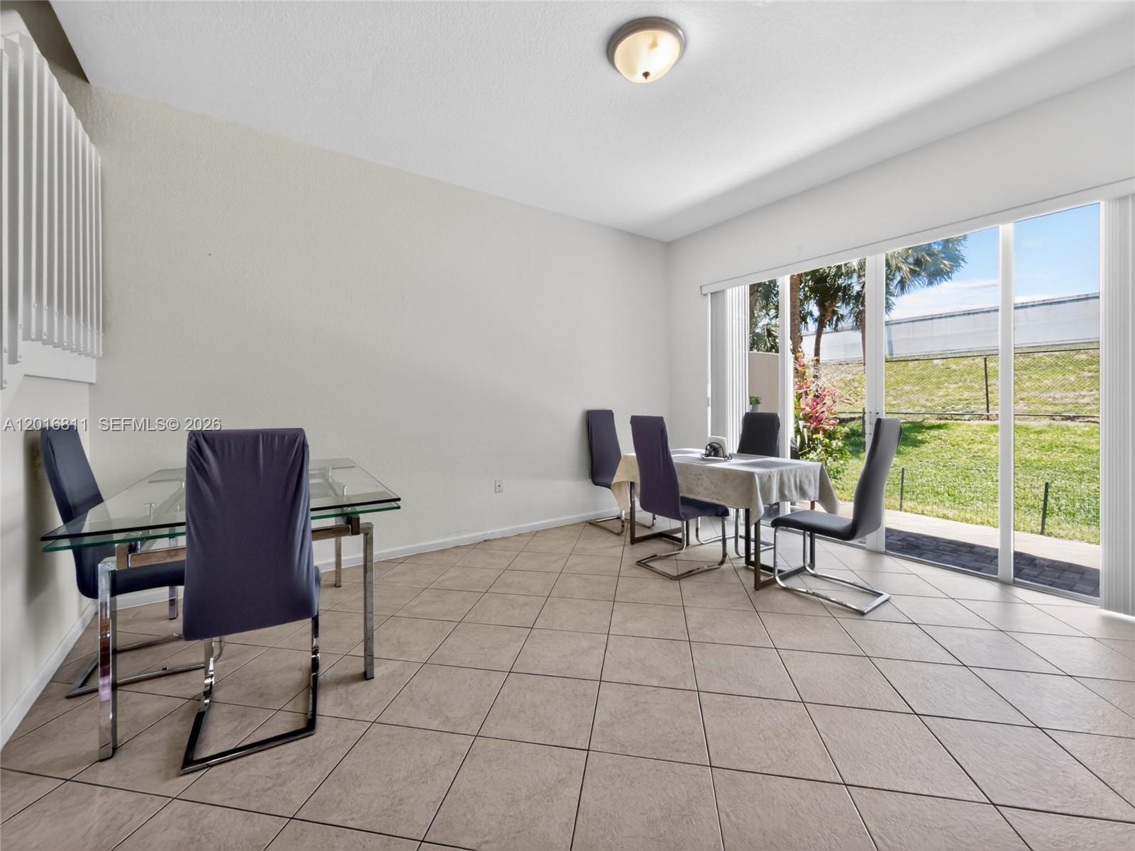 A dining area features tile floors, a glass table, and sliding doors to a backyard — 12415 SW 42nd St, Miramar FL 33027, MIRAMAR, FL