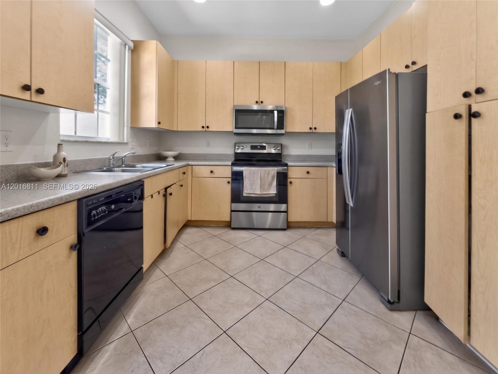 A kitchen features light wood cabinets, stainless steel appliances, and diagonal tile flooring — 12415 SW 42nd St, Miramar FL 33027, MIRAMAR, FL