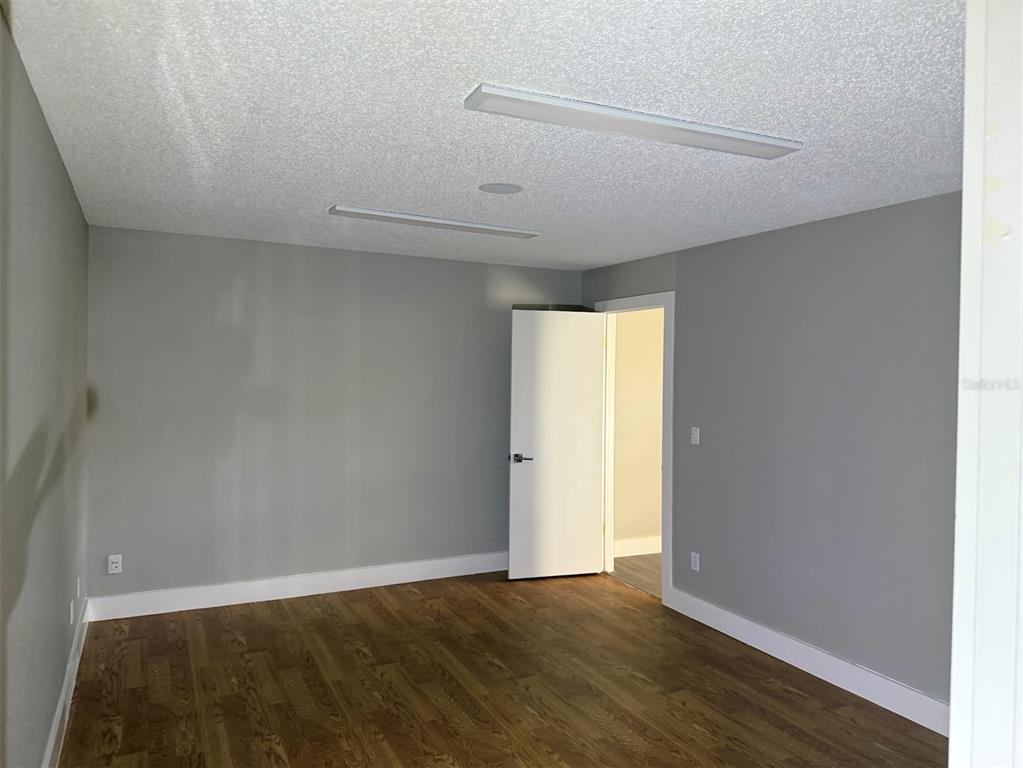 An empty room with gray walls, wood-look flooring, and two rectangular ceiling light fixtures — 2801 SW COLLEGE ROAD UNIT 22, OCALA, FL