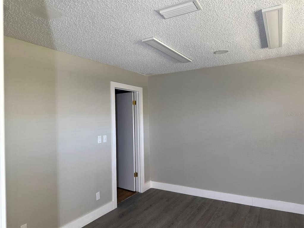An empty room with gray walls, dark wood-look flooring, and a textured white ceiling — 2801 SW COLLEGE ROAD UNIT 22, OCALA, FL