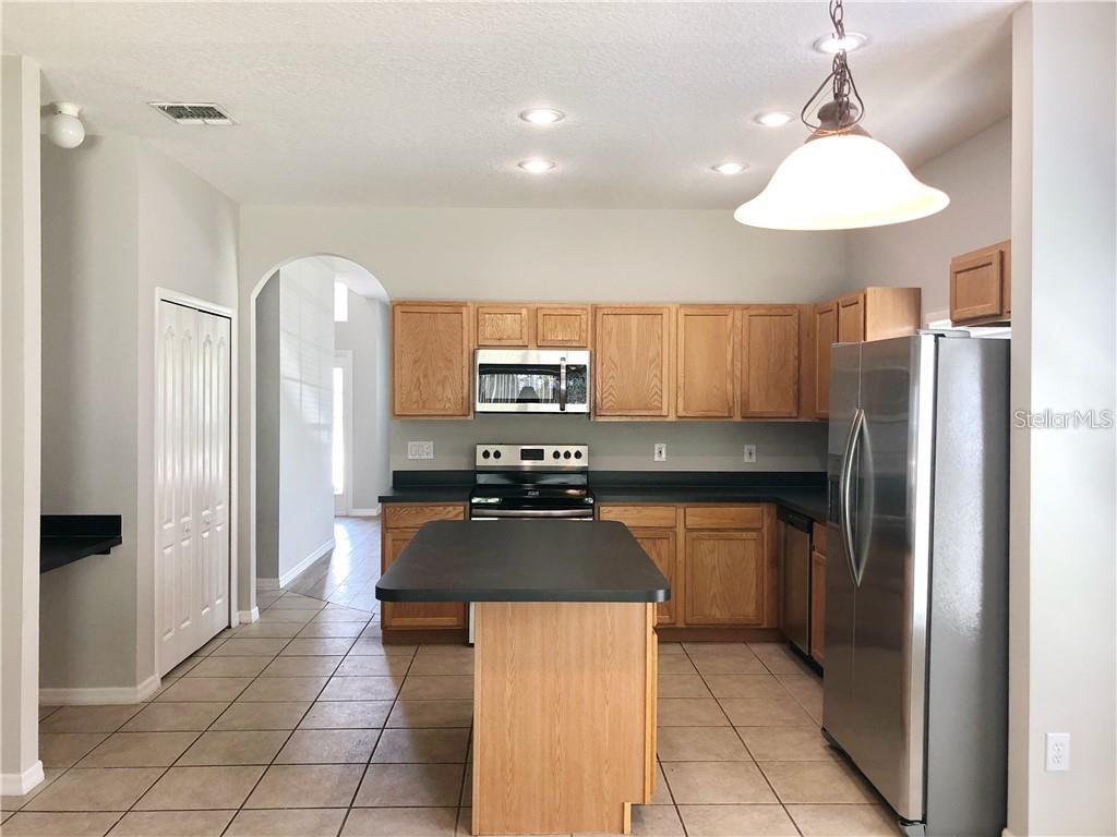 A kitchen features oak cabinets, black countertops, stainless steel appliances, and a central island — 112 BELGIAN WAY, SANFORD, FL