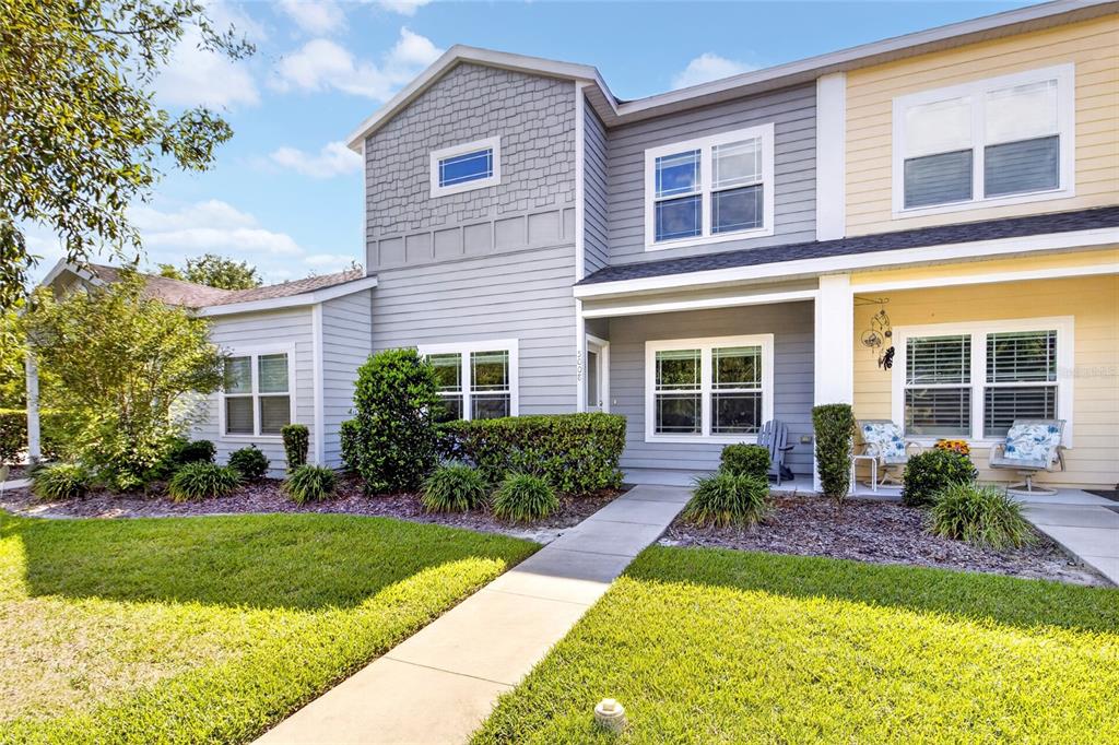 A two-story townhouse with gray and yellow siding, a front walkway, and landscaped bushes — 5008 NW 21ST DRIVE, GAINESVILLE, FL