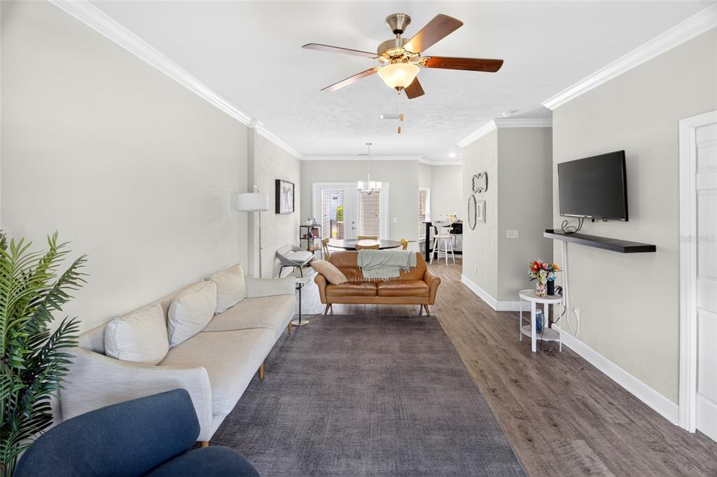 A living room features a light-colored sofa, a brown leather loveseat, and wood-look flooring — 5008 NW 21ST DRIVE, GAINESVILLE, FL