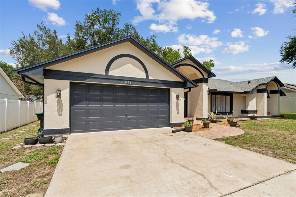 A single-story house with a two-car garage, beige stucco walls, and dark trim — 1426 JUBAL DRIVE, ORLANDO, FL