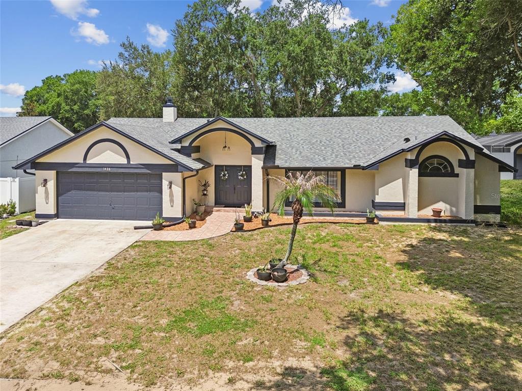 A single-story house with a gray garage, arched entryways, and a paved walkway — 1426 JUBAL DRIVE, ORLANDO, FL