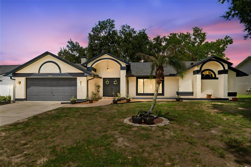 A single-story house with a two-car garage, arched entryways, and a palm tree in front — 1426 JUBAL DRIVE, ORLANDO, FL