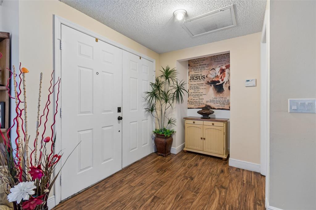 An entryway features wood-look flooring, a double front door, and a small wooden cabinet — 1426 JUBAL DRIVE, ORLANDO, FL