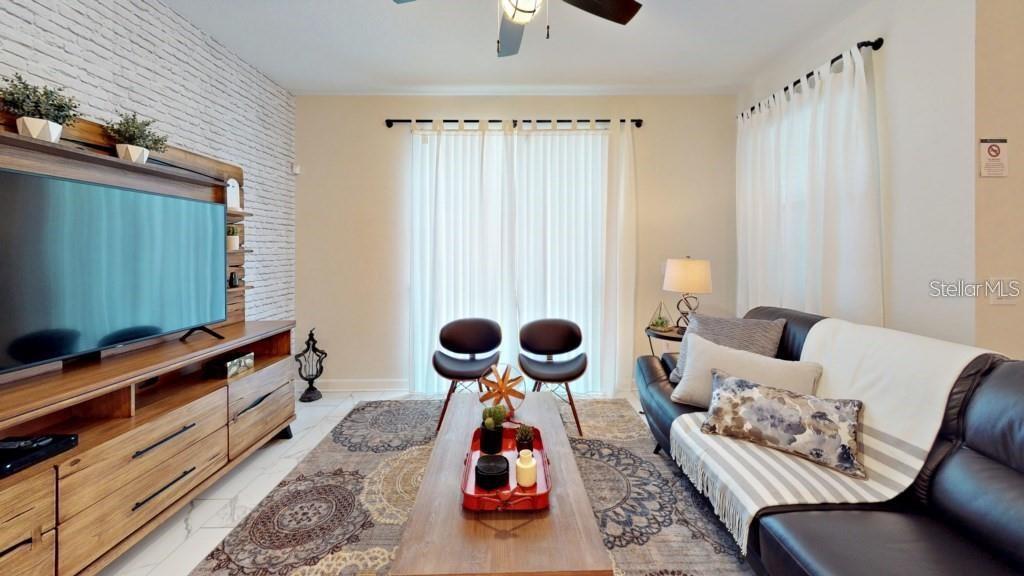 A living room features a brick accent wall, wood media console, and a black sofa — 4966 WINDERMERE AVENUE, KISSIMMEE, FL