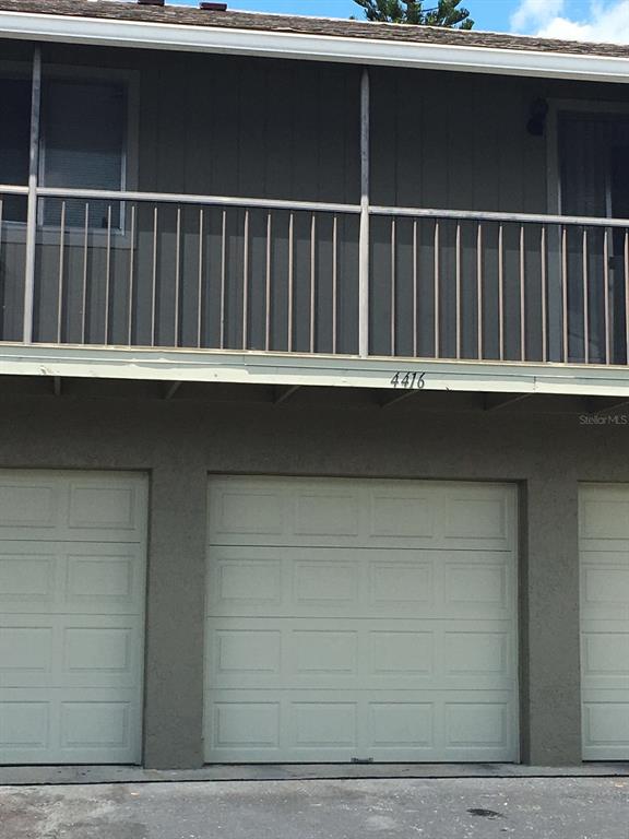 The exterior of a two-story building features a balcony above three closed garage doors — 4416 RING NECK ROAD UNIT 18B, ORLANDO, FL