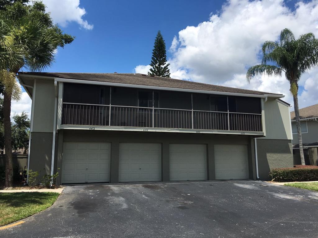 A two-story building features four garage doors on the ground level and a screened balcony above — 4416 RING NECK ROAD UNIT 18B, ORLANDO, FL