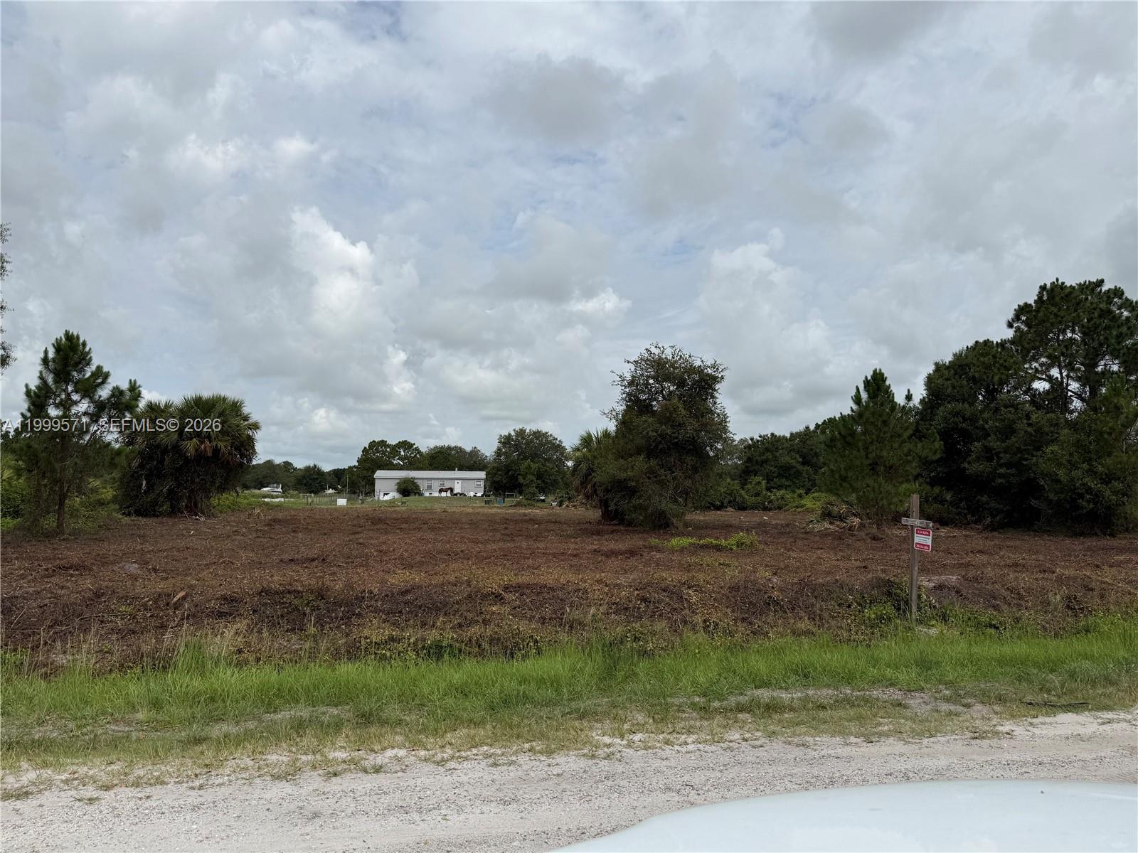 A cleared, vacant lot with scattered trees and a house visible in the distance — 760 N NOGAL ST, Clewiston FL 33440, CLEWISTON, FL