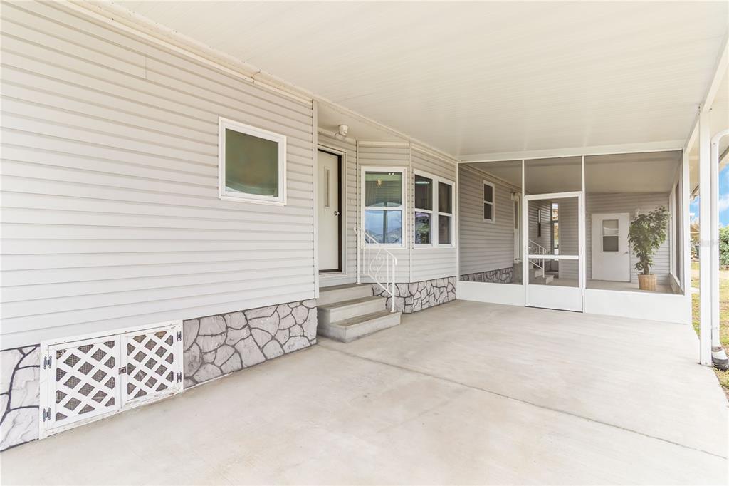 A concrete patio area features a screened-in porch, light gray siding, and stone-patterned skirting — 2517 INDEPENDENCE LANE, ST CLOUD, FL
