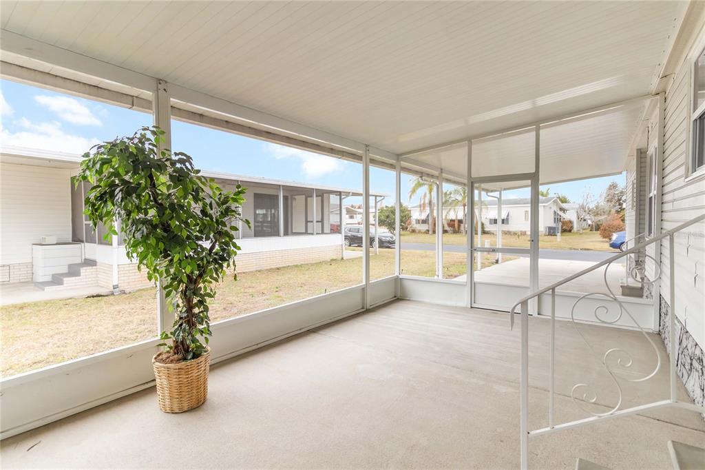 A screened-in porch with a concrete floor, white metal framing, and a potted plant — 2517 INDEPENDENCE LANE, ST CLOUD, FL