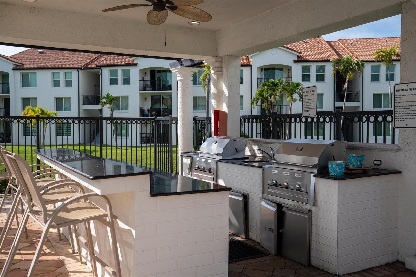 An outdoor kitchen features stainless steel grills, a black granite bar, and white brick counters — 809 Villa Circle, Boynton Beach FL 33435, BOYNTON BEACH, FL