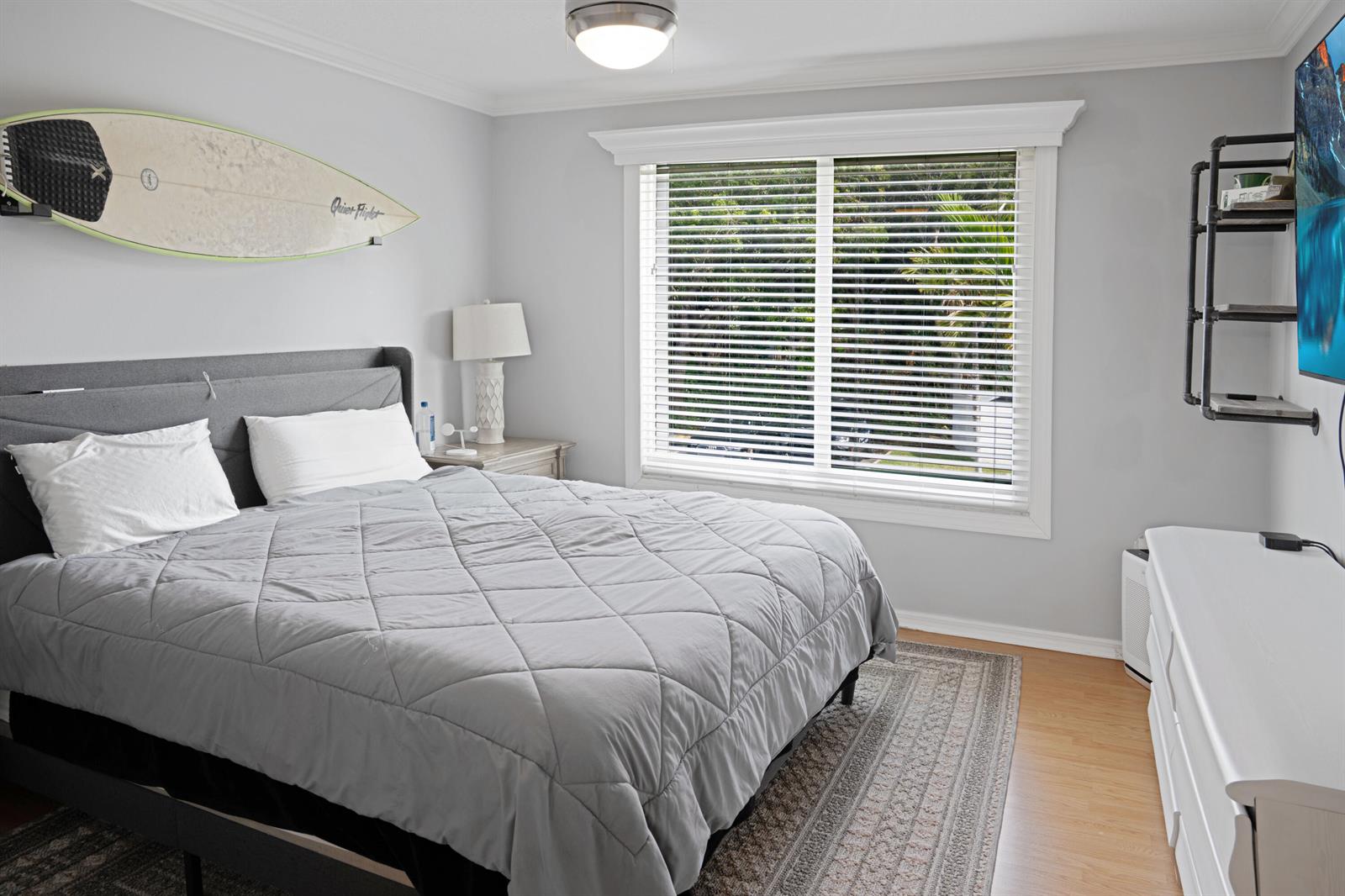 A bedroom features a gray bed, a surfboard wall decoration, and a window with blinds — 809 Villa Circle, Boynton Beach FL 33435, BOYNTON BEACH, FL