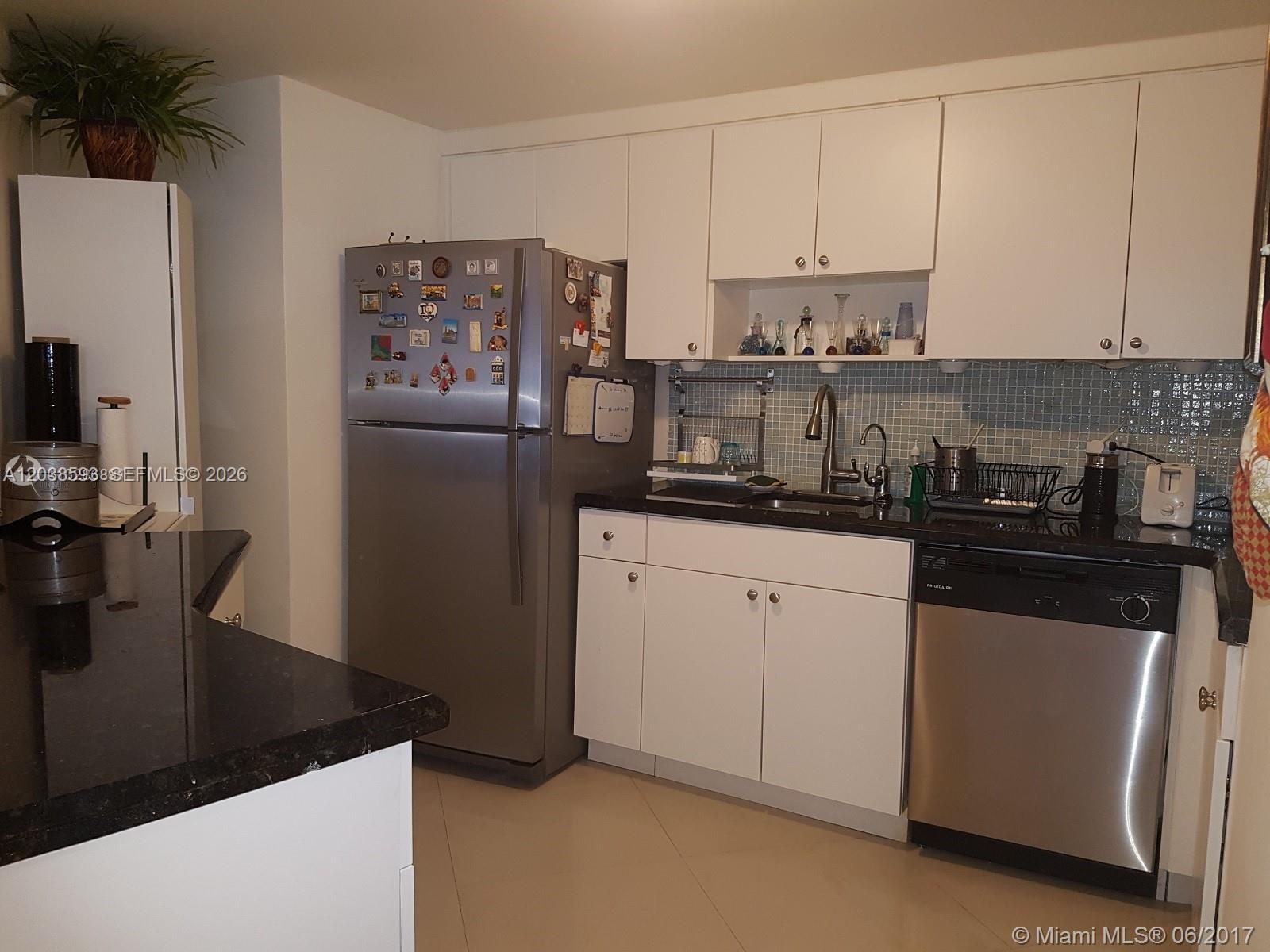 A kitchen features white cabinets, stainless steel appliances, and black countertops with a tiled backsplash — 801 Brickell Bay Dr # 765, Miami FL 33131, MIAMI, FL