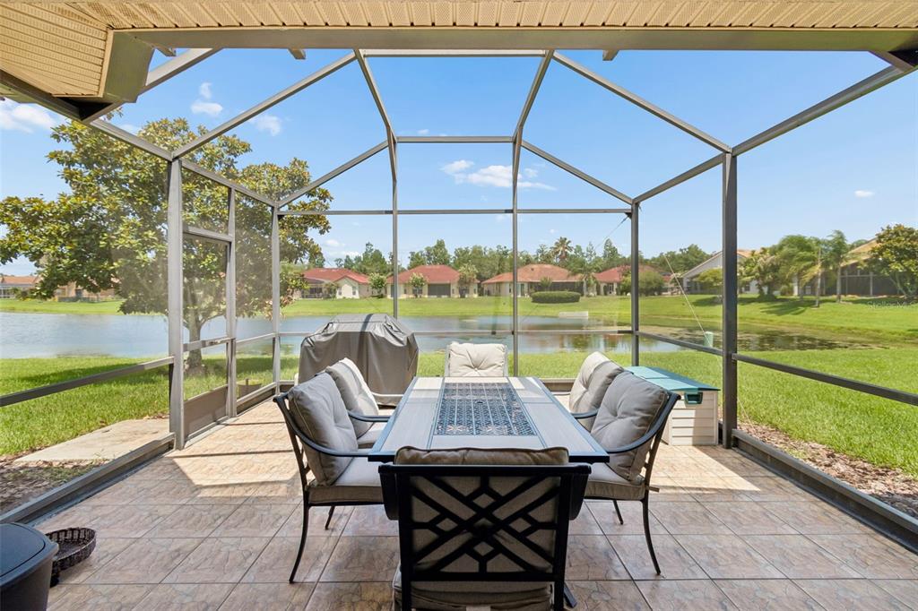 A screened-in patio features a dining set, tiled flooring, and a view of a lake — 518 DAVINCI PASS, KISSIMMEE, FL