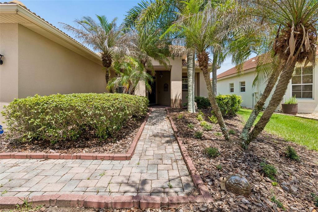 A paved walkway leads to the front entrance of a house with palm trees — 518 DAVINCI PASS, KISSIMMEE, FL