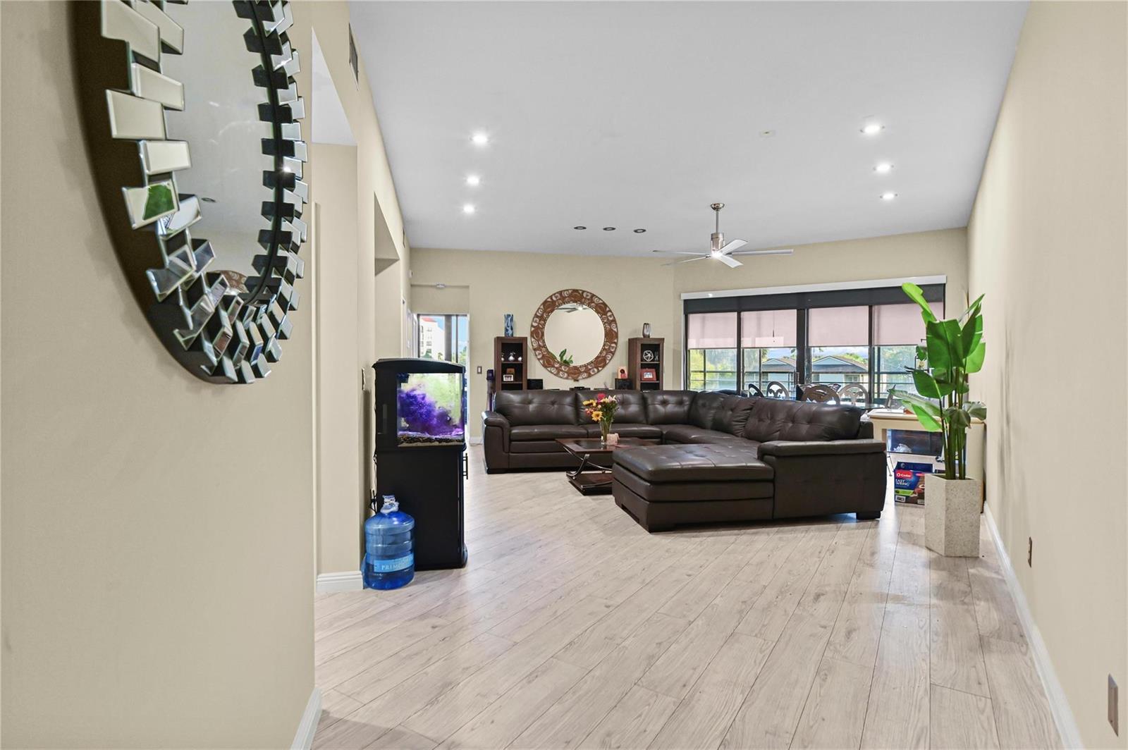 A living room features light wood-look flooring, a large brown sectional, and a fish tank — 7520 La Paz Boulevard # 306, Boca Raton FL 33433, BOCA RATON, FL