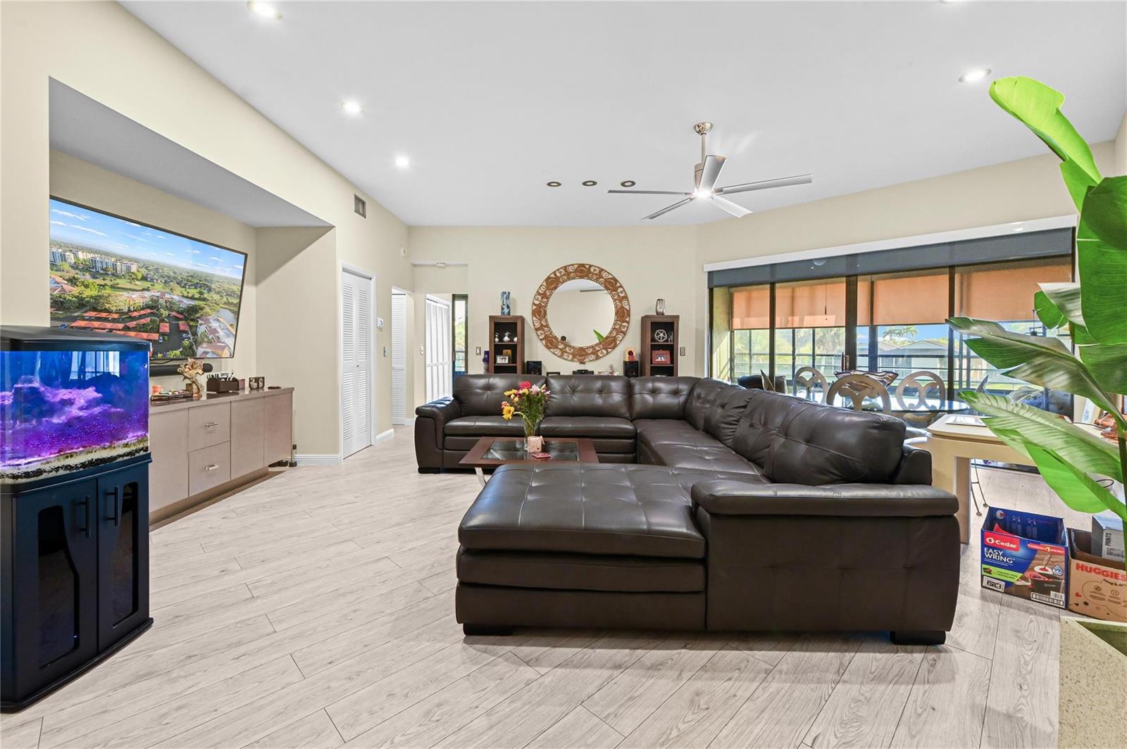 A living room features a large brown sectional sofa, a television, and light wood flooring — 7520 La Paz Boulevard # 306, Boca Raton FL 33433, BOCA RATON, FL