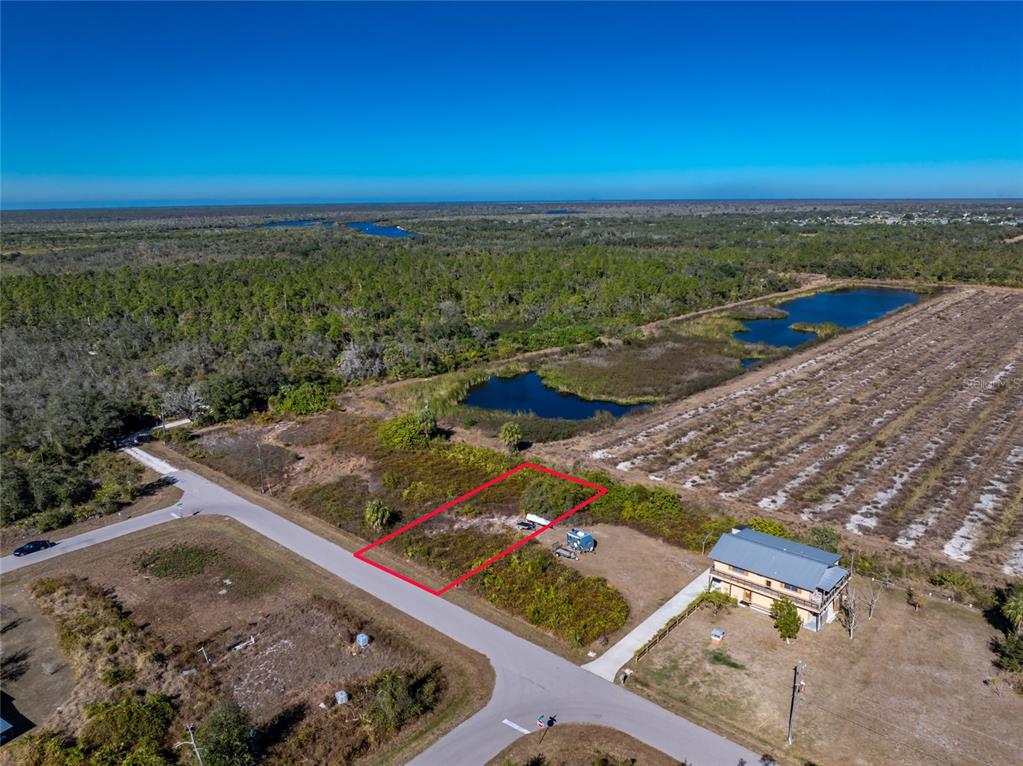 An aerial view shows a vacant rectangular lot outlined in red next to a house — 29028 BOYCE ROAD, PUNTA GORDA, FL