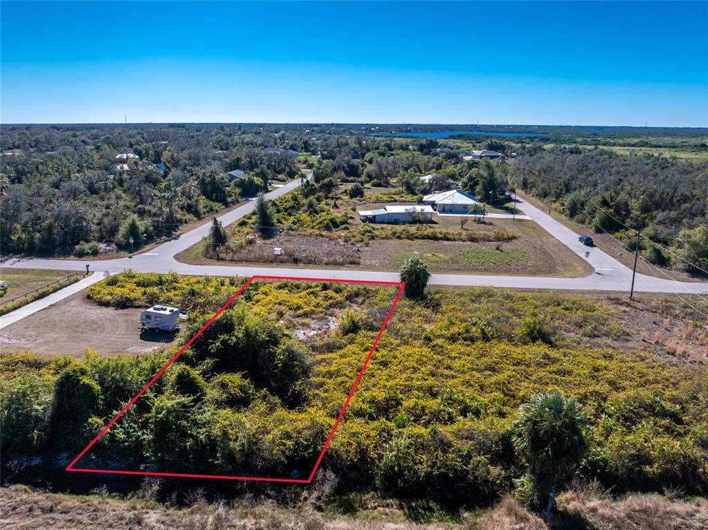 An aerial view shows a vacant, overgrown rectangular lot outlined in red near a road — 29028 BOYCE ROAD, PUNTA GORDA, FL