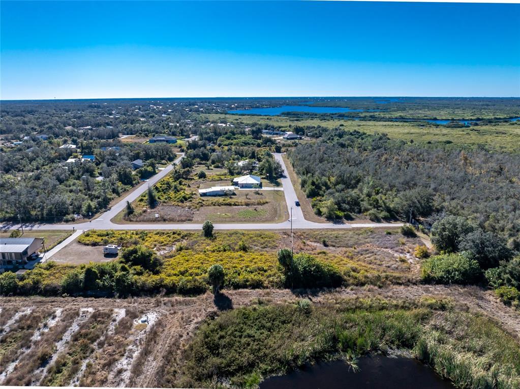An aerial view shows a residential lot with a house, surrounding vegetation, and a pond — 29028 BOYCE ROAD, PUNTA GORDA, FL