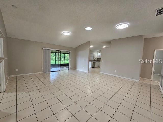 An open-concept living area features light-colored tile flooring, recessed lighting, and a sliding glass door — 10148 PINK CARNATION COURT, ORLANDO, FL