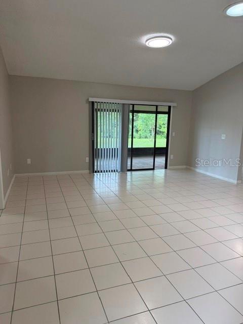 An empty room with light-colored tile flooring and a sliding glass door leading outside — 10148 PINK CARNATION COURT, ORLANDO, FL