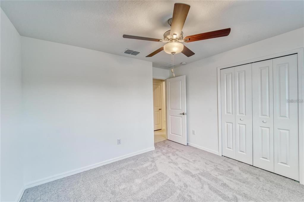 A bedroom with white walls, gray carpet, a ceiling fan, and white closet doors — 5514 BLUE AZURE DRIVE, WIMAUMA, FL